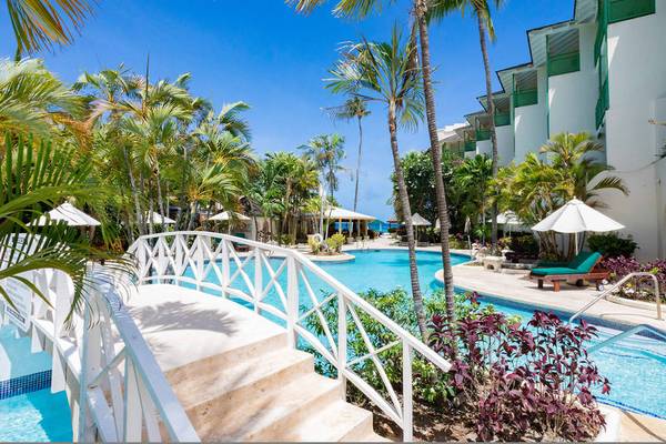 Außenbereich des Mango Bay Hotels mit Pool, Sonnenliegen und Palmen