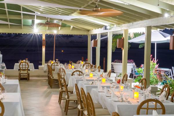Innenbereich des Restaurants im Mango Bay Hotel bei Nacht mit gedeckten Tischen und stimmungsvoller Beleuchtung.