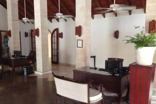 Lobby des Mango Bay Hotels mit Schreibtisch, Stuhl, Pflanzen und Deckenventilatoren.
