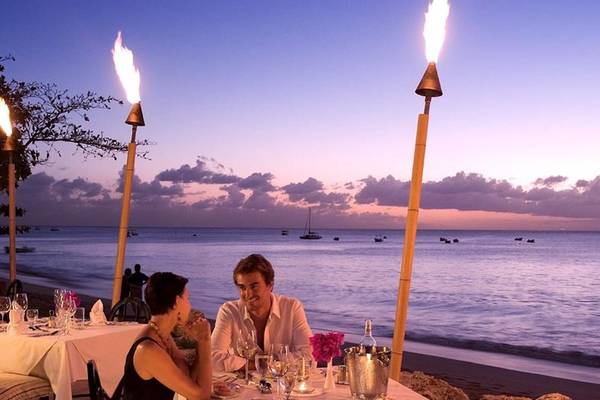 Paar sitzt beim Abendessen am Strand im Mango Bay Hotel mit Blick auf das Meer.