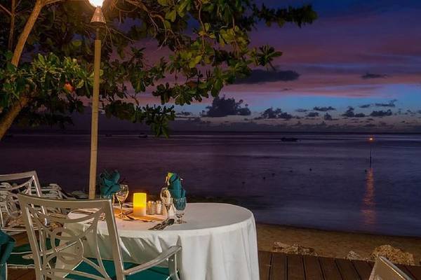 Mango Bay Hotel Terrasse mit Tisch für Abendessen und Blick auf den Ozean bei Sonnenuntergang.