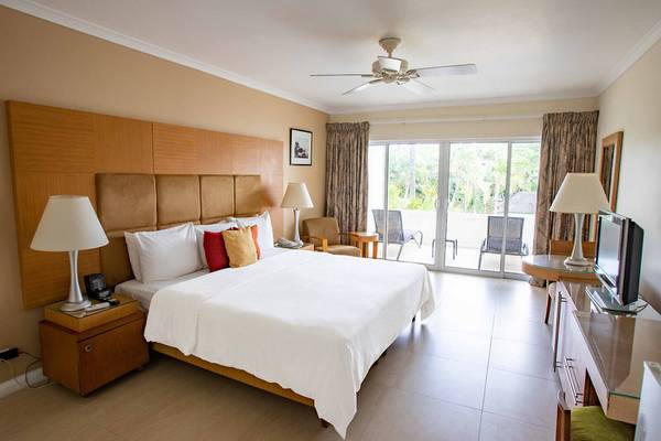 Schlafzimmer im Mango Bay Hotel mit großem Bett, Lampen und Fernseher.