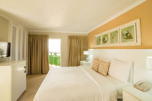 Schlafzimmer im Mango Bay Hotel mit Bett, Fernseher und Balkonzugang