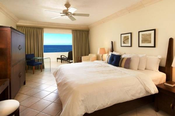 Schlafzimmer im Mango Bay Hotel mit Meerblick, inklusive Bett, Nachttischen, Lampe und Möbeln.