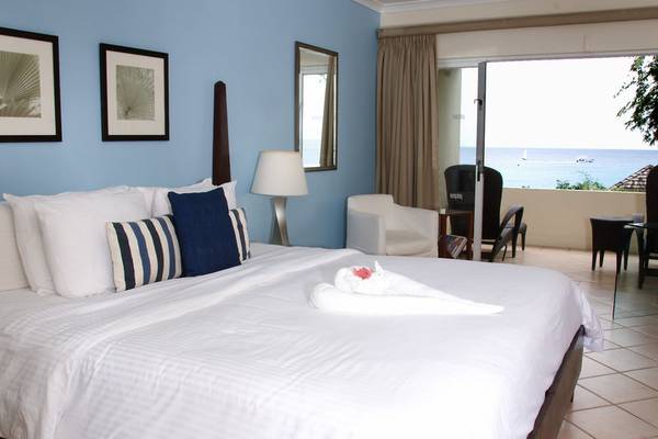 Schlafzimmer im Mango Bay Hotel mit Blick auf das Meer und eine Terrasse mit Möbeln.