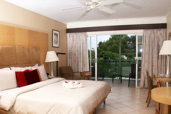 Schlafzimmer im Mango Bay Hotel mit Bett, Nachttischen, Lampe und Balkon