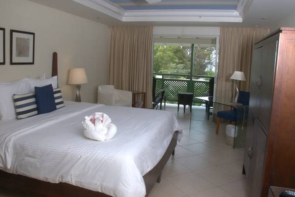 Schlafzimmer im Mango Bay Hotel mit großem Bett, Balkon und Blick auf den Garten.