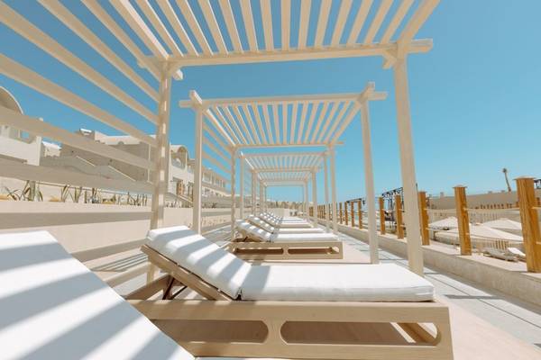 Lounge-Bereich im Freien des Sunrise Anjum Resort mit weißen Liegestühlen und Sonnenschutz.