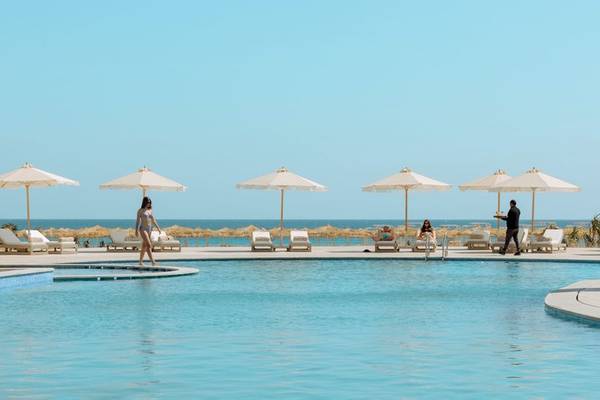 Außenpool am Strand des SUNRISE Anjum Resort mit Gästen und Sonnenschirmen.