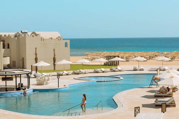 Außenpool und Strandbereich des Sunrise Anjum Resort mit Sonnenschirmen und Liegestühlen.