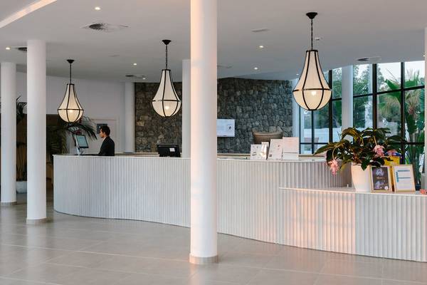 Empfangsbereich des AluaSoul Ibiza Hotels mit Rezeptionstresen, Angestelltem, Pflanzen und Lampen.