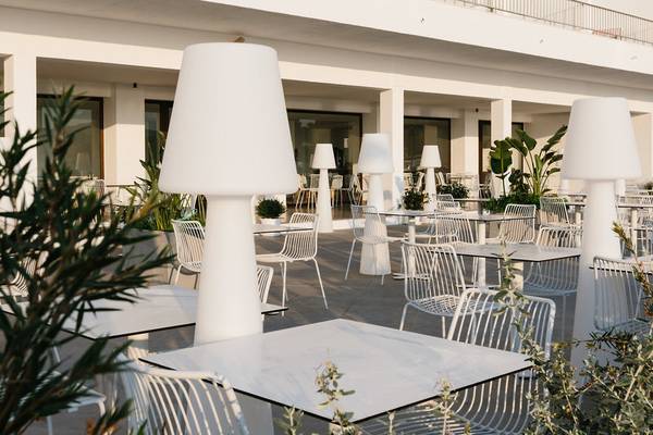 Außenterrasse des AluaSoul Ibiza Hotels mit weißen Tischen und Stühlen.