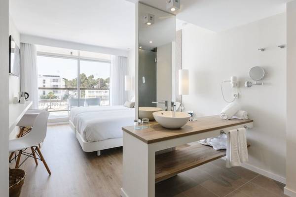 Badezimmer im AluaSoul Ibiza Hotel mit zwei Waschbecken, einem Bett und Ausblick auf die Stadt.