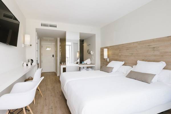 Modernes Hotelzimmer im AluaSoul Ibiza mit zwei Betten, Schreibtisch und Fernseher.