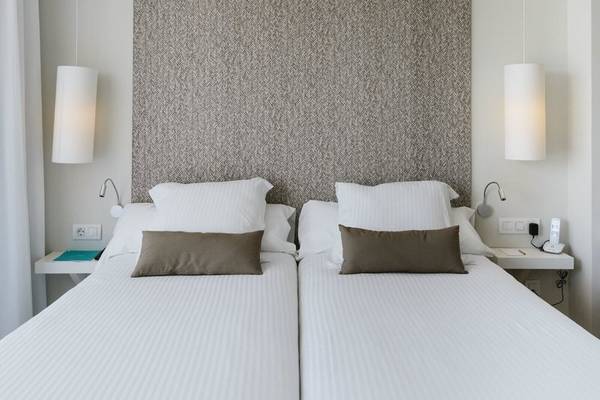 Doppelbett-Schlafzimmer im AluaSoul Ibiza Hotel mit weißen Laken und Kissen.