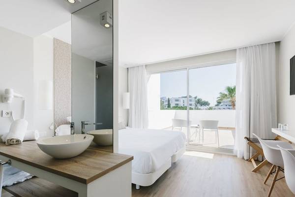 Innenansicht eines Hotelzimmers im AluaSoul Ibiza mit Bett, Waschbecken und Terrassentür.