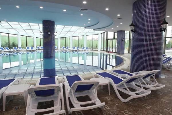 Poolbereich des Alan Xafira Deluxe Resort & Spa mit blauen Liegestühlen und Säulen