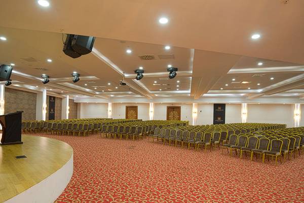 Ein Saal im Alan Xafira Deluxe Resort & Spa mit roten Teppich und Reihen von Stühlen.
