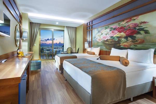 Hotelzimmer im Alan Xafira Deluxe Resort & Spa mit zwei Betten, einem Tisch und einem großen Blumenbild an der Wand.