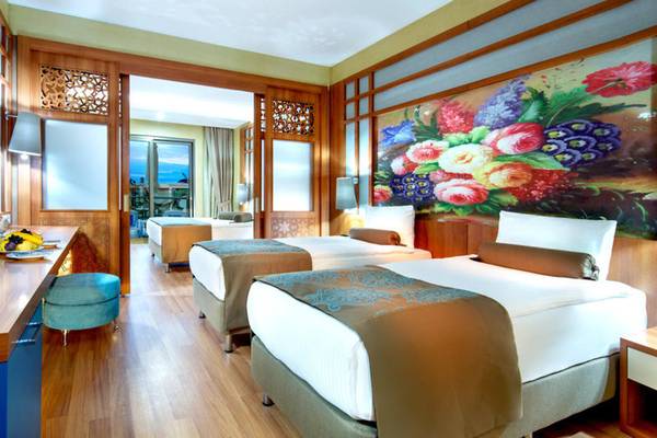 Ein elegantes Hotelzimmer mit Blumenwand und Meerblick, zwei Betten, einem Schreibtisch und einem Stuhl.