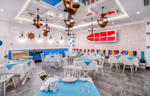 Innenbereich des Restaurants im Sensitive Premium Resort & Spa mit blau-weißen Tischdecken und maritimen Dekorationen.