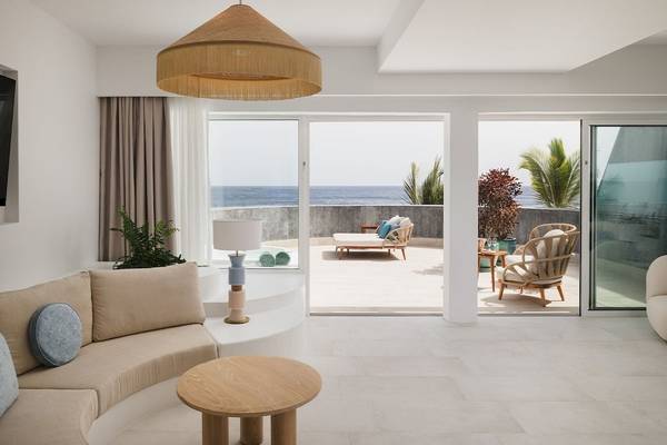 Wohnbereich des Plus Fariones Suite Hotels mit Blick auf das Meer und moderne Inneneinrichtung.