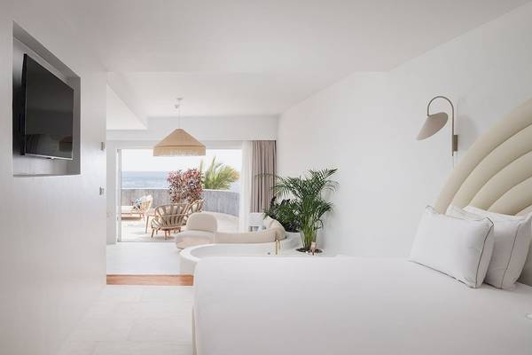 Innenraum des Plus Fariones Suite Hotel mit einem großen Bett, Pflanzen und Meerblick