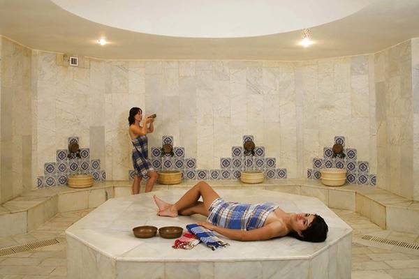 Eine Frau liegt im Dampfbad des Richmond Ephesus Resorts, während eine andere Frau dahinter steht.