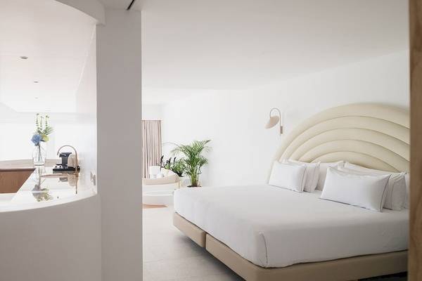 Schlafzimmer im Plus Fariones Suite Hotel mit weißem Bett, Dekor und Pflanzen.