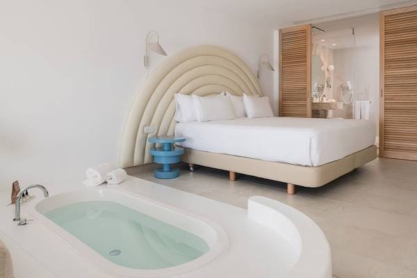 Schlafzimmer im Plus Fariones Suite Hotel mit Bett, Badewanne und Badezimmertür
