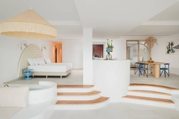 Innenansicht des Schlafzimmers im Plus Fariones Suite Hotel mit Badewanne, Bett und Esstisch.
