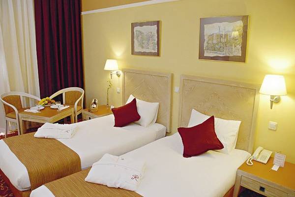 Zwei Betten mit roten Kissen in einem gelb gestrichenen Zimmer im Richmond Ephesus Resort.