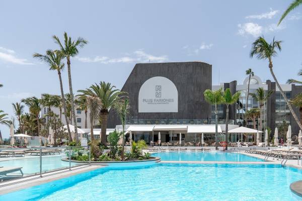 Außenansicht des Plus Fariones Suite Hotel mit Swimmingpool, Sonnenliegen und Palmen