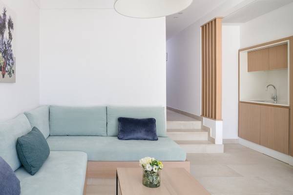 Innenraum des Plus Fariones Suite Hotel mit einem blauen Sofa und einem Tisch mit Blumenvase.