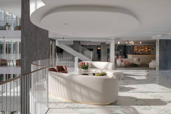 Plus Fariones Suite Hotel Lobby mit weißen Möbeln, Blumen und Marmorboden.