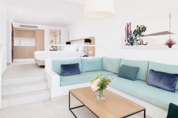 Innenbereich des Plus Fariones Suite Hotels mit hellem Design, Sofa, Couchtisch und Bett.