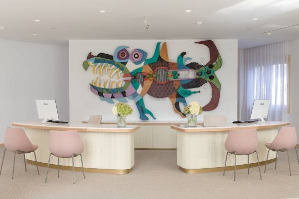 Empfangsbereich des Plus Fariones Suite Hotels mit buntem Wandbild und modernen Schreibtischen.