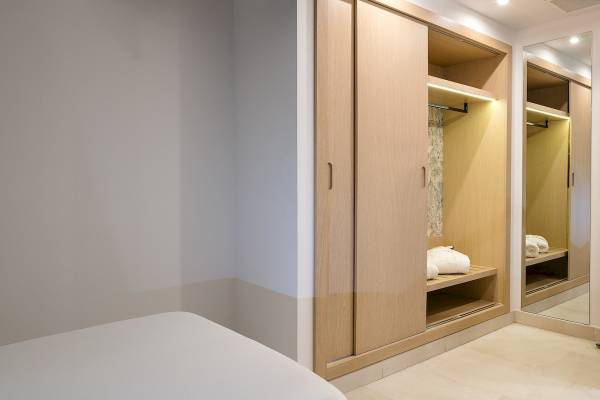 Schlafzimmer im Plus Fariones Suite Hotel mit einem Kleiderschrank und Spiegel