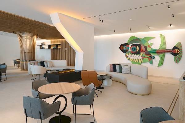 Lobby des Plus Fariones Suite Hotels mit modernen Möbeln und einer großen Wandmalerei.