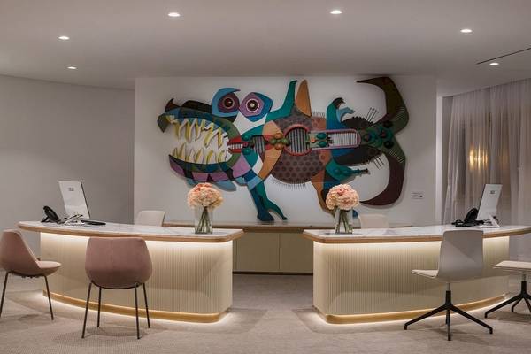 Rezeption im Plus Fariones Suite Hotel mit großem Wandbild, Marmortheken und modernen Stühlen.