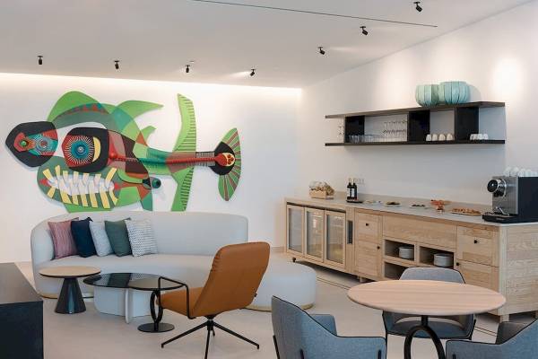 Innenraum des Plus Fariones Suite Hotel mit moderner Einrichtung, buntem Wandbild und weißen Möbeln.
