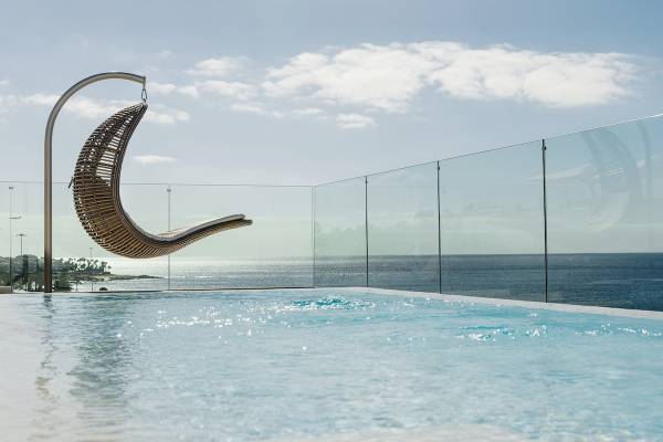 Außenpool des Plus Fariones Suite Hotels mit Hängesessel und Meerblick.