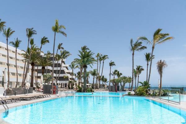 Außenpool des Plus Fariones Suite Hotels mit Loungeliegen und Palmen