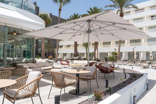 Lounge Bereich des Plus Fariones Suite Hotels mit weißen Möbeln und großen Sonnenschirm.
