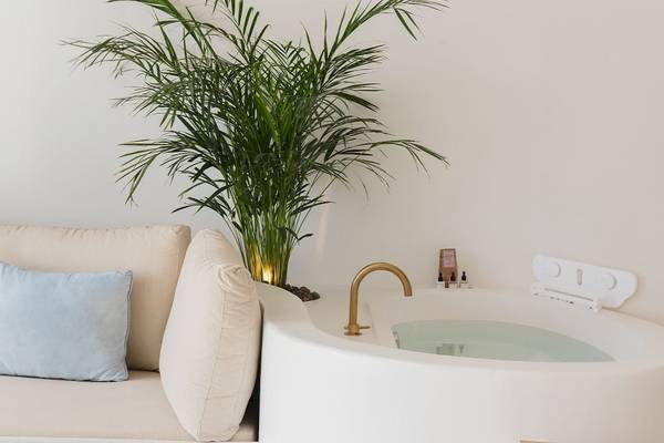 Ein modernes Hotelzimmer mit weißem Sofa, blauem Kissen und großer Badewanne