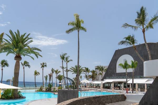 Außenpool des Plus Fariones Suite Hotel mit Palmen und Blick auf das Meer.