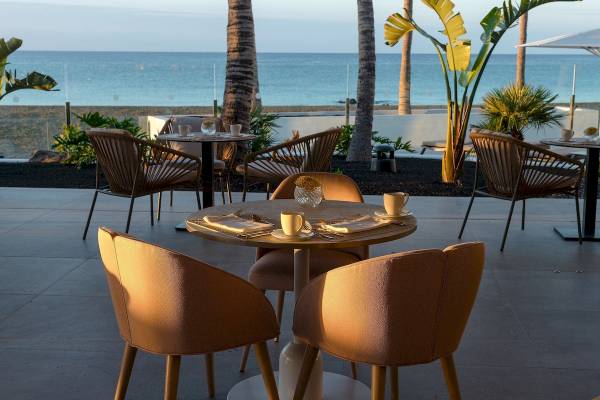 Terrasse des Plus Fariones Suite Hotels mit Blick auf das Meer und gesellige Tischanordnungen.