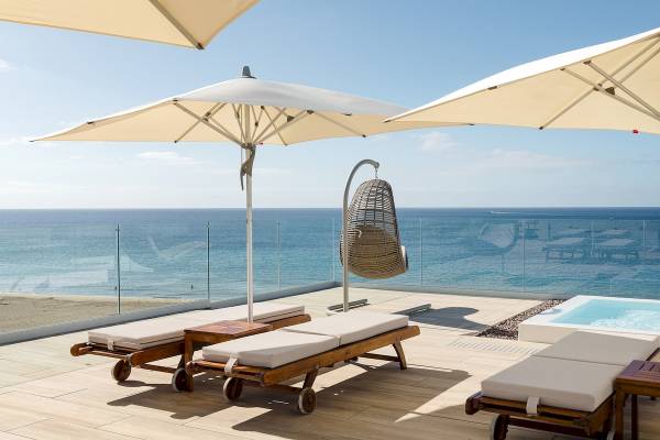 Terrasse des Plus Fariones Suite Hotels mit Liegen, Sonnenschirmen und Whirlpool mit Meerblick