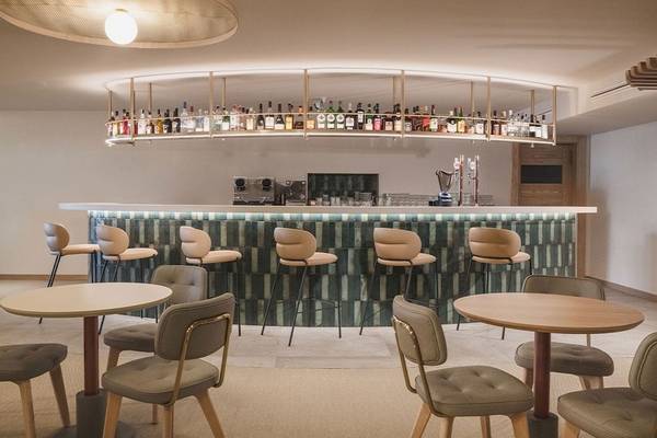 Barbereich des Plus Fariones Suite Hotels mit grüner Wand und vielen Flaschen.