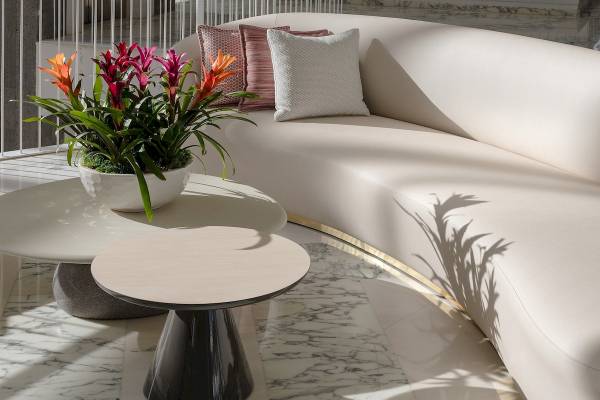 Inneneinrichtung des Plus Fariones Suite Hotel mit weißem Sofa, Beistelltischen und Blumenvase.